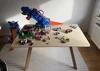 Ein Kindertisch ist voller bunter Spielzeuge wie Autos und einem Dinosaurier.