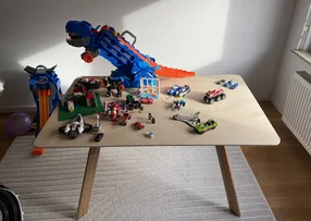 Ein Kindertisch ist voller bunter Spielzeuge wie Autos und einem Dinosaurier.