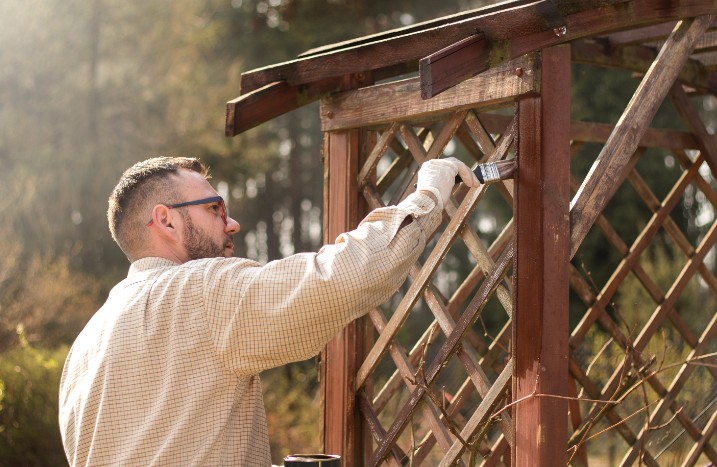 Mann streicht Pergola