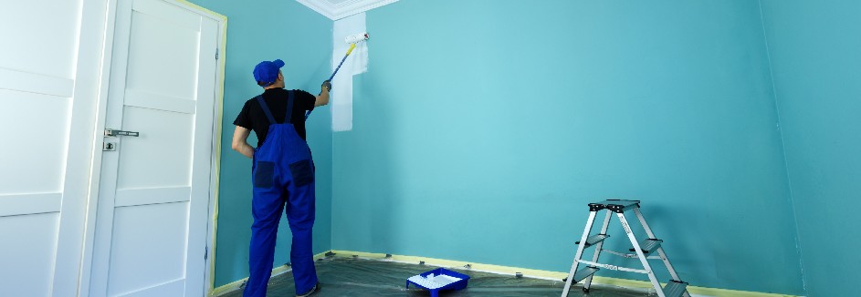 Maler streicht hellblaues Zimmer weiß