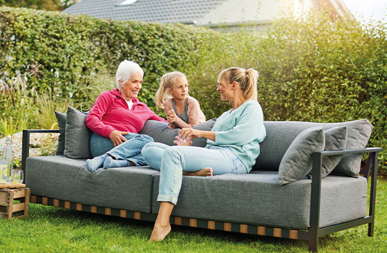 Frauen sitzen auf grauem Sofa im Garten