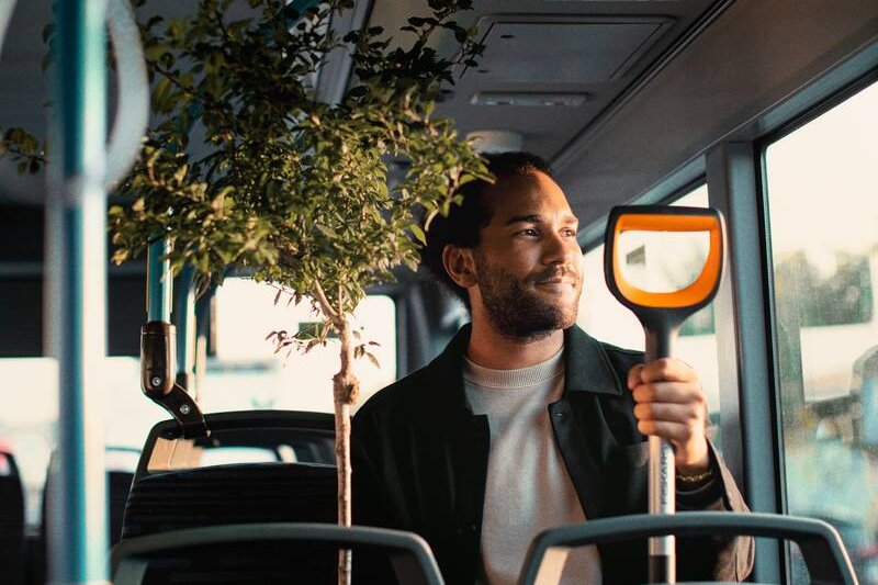 Person im Bus mit Bäumchen und Spaten