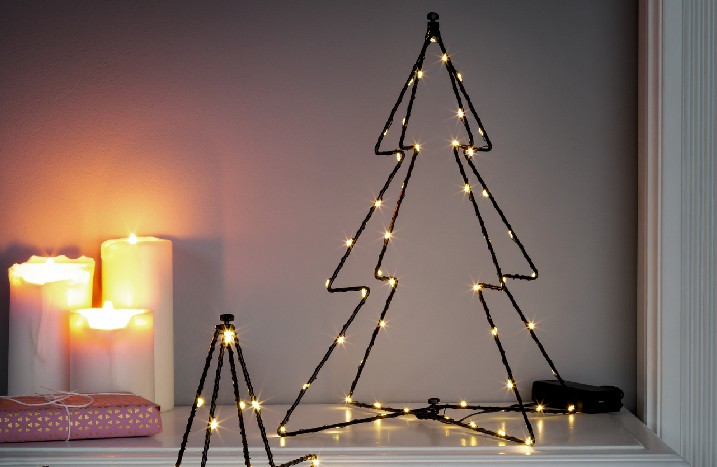 Weihnachtliche Lichtdeko neben Kerzen im Wohnzimmer.