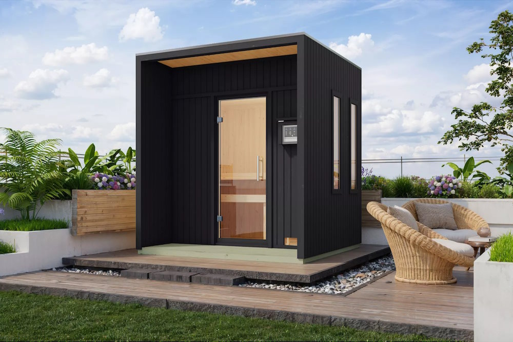 Eine dunklegraue Sauna von Karibu steht in einem Außenbereich