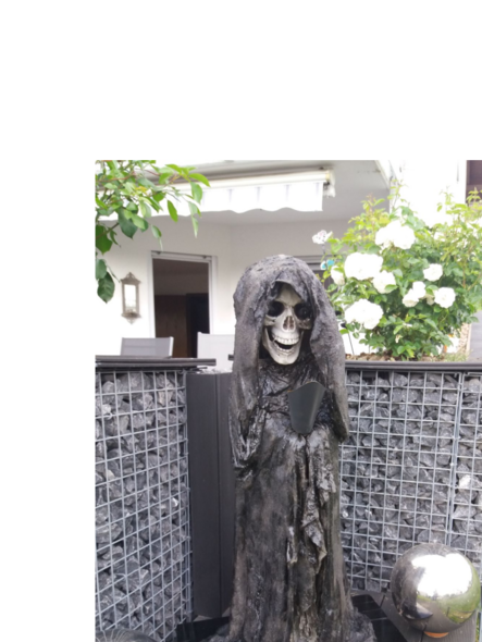 Skelettfigur mit Sense in einem Garten