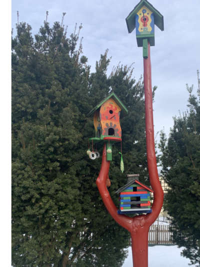 Drei bunte Vogelhäuser auf einem roten Stamm