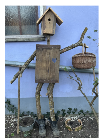 Vogelscheuche aus Holz mit Vogelhaus als Kopf.