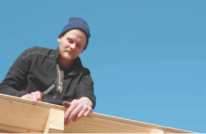 Ein Zimmermann befestigt ein Dach auf dem Gartenhaus.