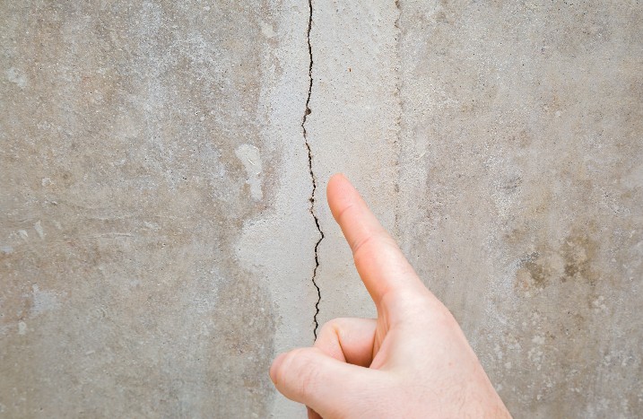 Hand zeigt auf Riss in Wand Fassade