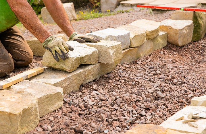 Mann baut Trockenmauer aus Naturstein