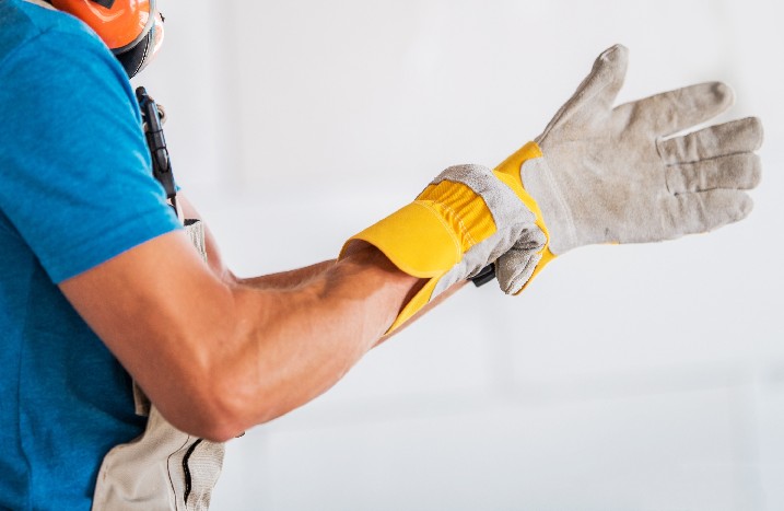 Arbeiter zieht Schutzhandschuhe an.