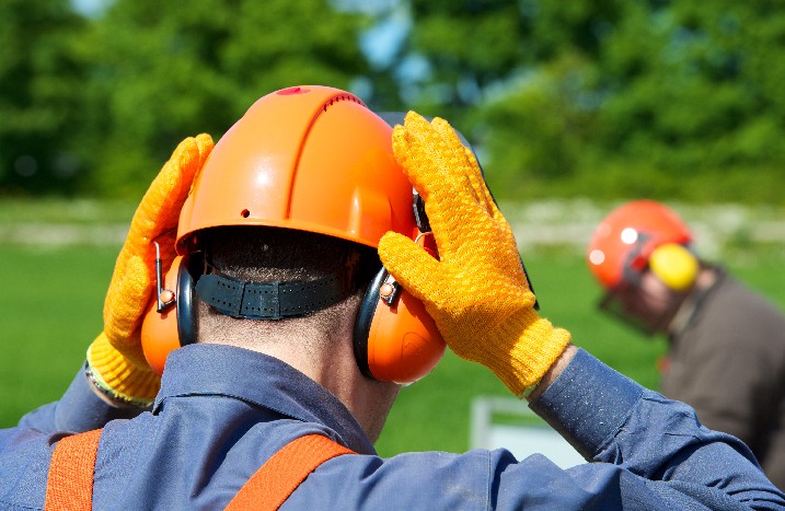 Arbeiter setzt sich Gehörschutz auf