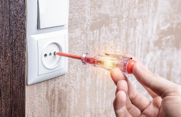 Arbeiter benutzt Spannungsprüfer, um die Steckdose zu überprüfen.
