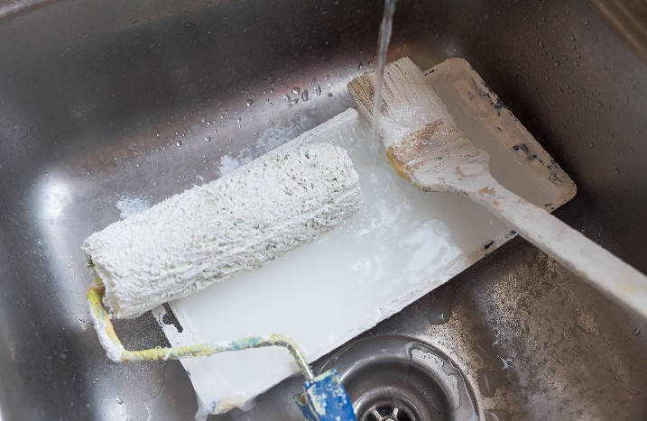 Benutztes Malerwerkzeug wird im Waschbecken gereinigt.