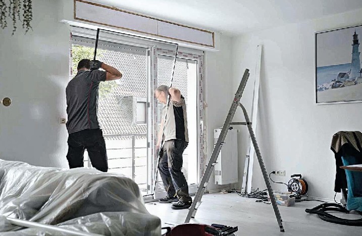 Zwei Männer setzen die Glasscheibe einer Schiebetür wieder ein.