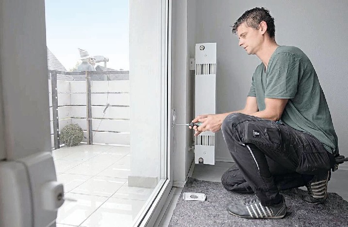 Ein Mann löst Schrauben, um eine Terrassentür auszubauen.