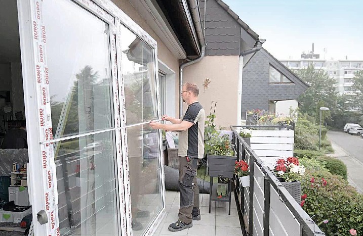 Handwerker misst die neue Terrassentür aus.