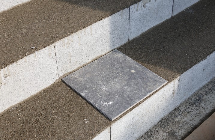 einzelne Fliese liegt auf Rohbautreppe