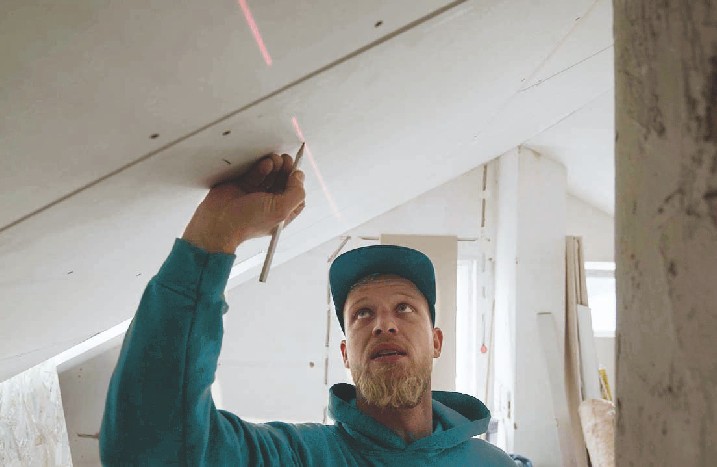Handwerker zeichnet mit Bleistift die Position einer Zwischenwand auf.