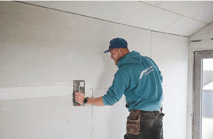 Handwerker beim Verspachteln der neuen Trennwand.