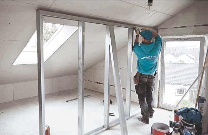 Ein Handwerker setzt die Rahmenkonstruktion für eine Trockenbauwand ein.