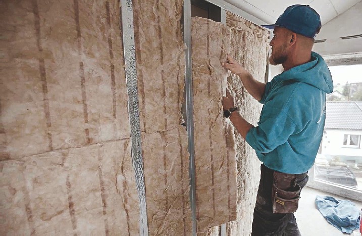 Der Handwerker füllt die neue Wand mit Dämmmaterial.