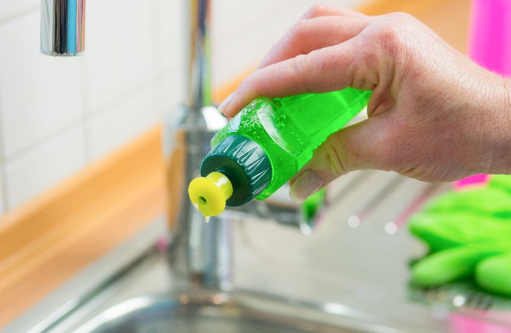 Hand füllt Spülmittel in Eimer