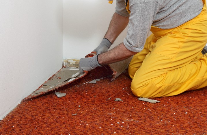 Handwerker entfernt Ecke vom Teppichboden