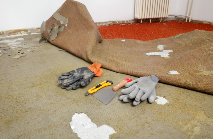 Handschuhe und Kratzer liegen vor entferntem Teppichboden