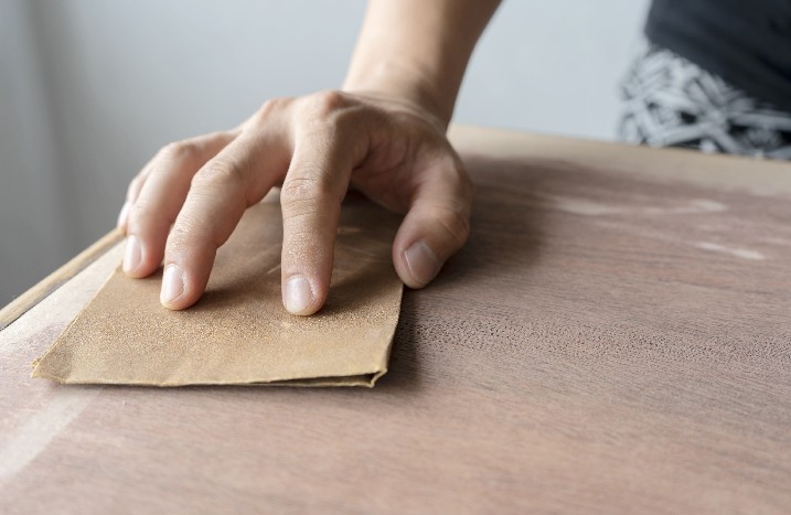 Holzoberfläche wird mit Schleifpapier bearbeitet