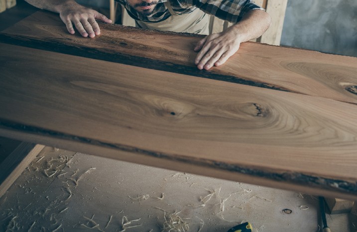 Mann überprüft Holz nach dem Schleifen