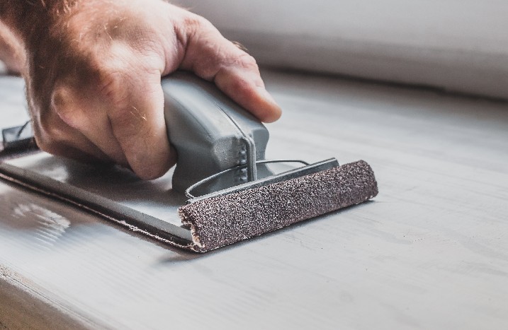 Nahaufnahme der Hand des Meisters mit Schleifleiste mit grobem Schleifpapier