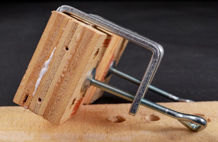 Holzstücke mit Holzleim sind fixiert durch Schraubzwingen