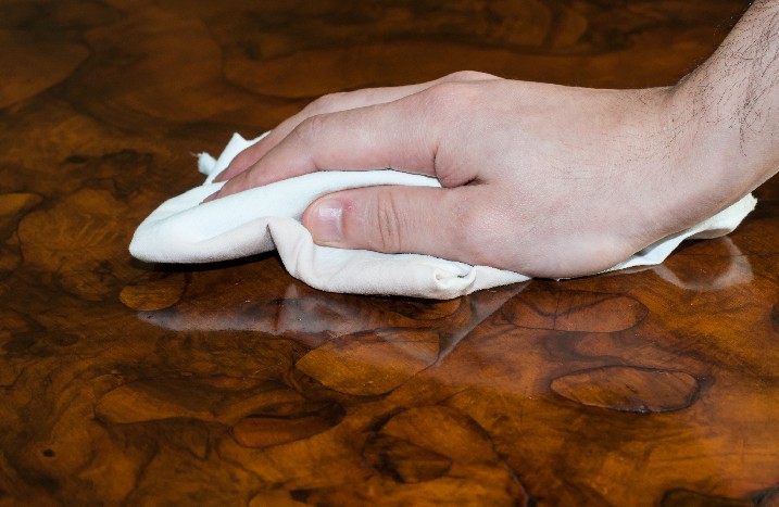 Hand mit Tuch auf Holzoberfläche