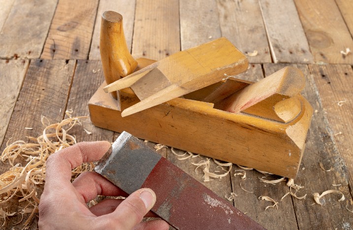 Hand mit Hobelmesser vor Holzhobel