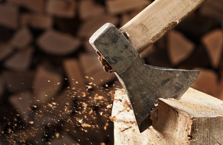 Nahaufnahme einer Axt beim Spalten eines Holzscheits.