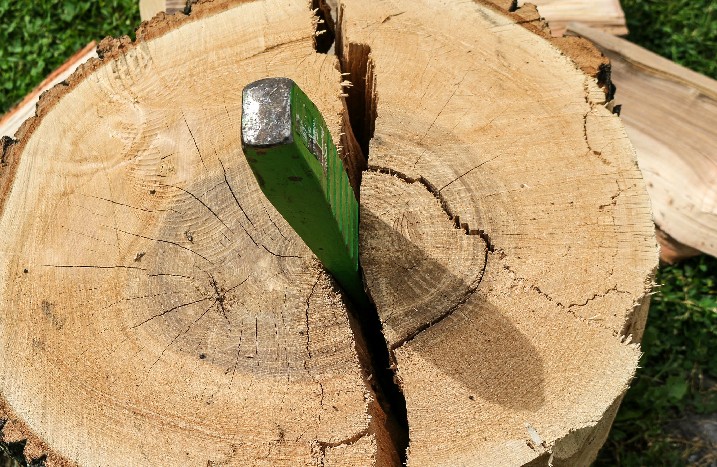 Ein Spaltkeil steckt in einem Stück Holz.