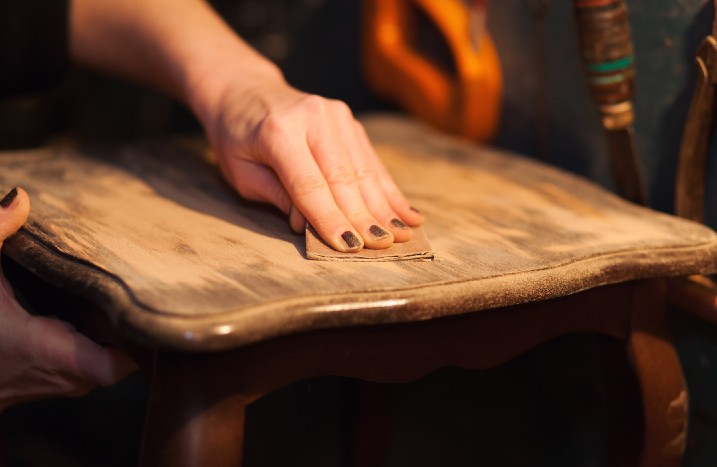 Alter Lack wird von Tisch mit Schleifpapier entfernt