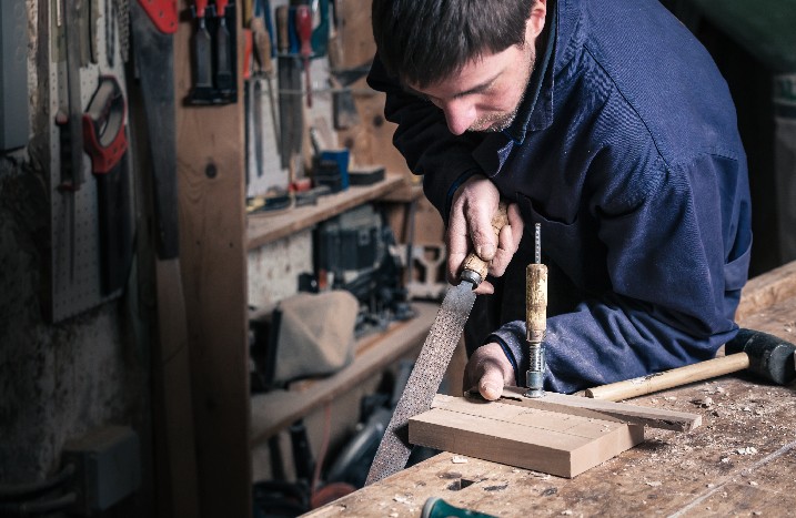 Mann raspelt Holzblock