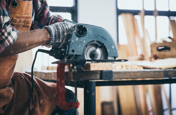 Mann sägt mit Handkreissäge Holz.