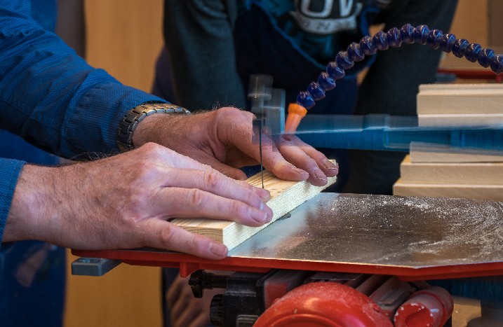Hand hält Holzstück in Dekupiersäge.