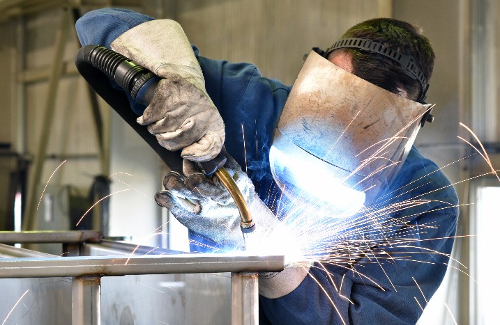 Mann schweißt Metall und Funken sprühen