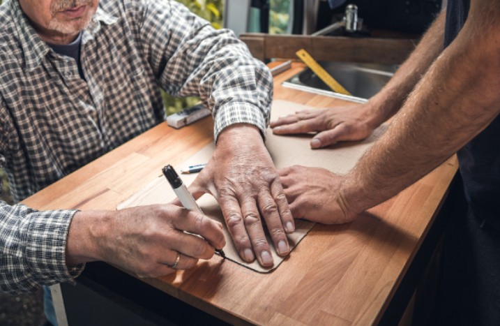 Arbeiter markieren Ausschnitt auf Arbeitsplatte