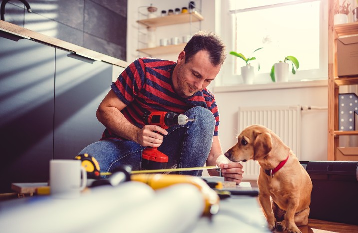 Mann und Hund sitzen in der Küche und planen die Renovierung