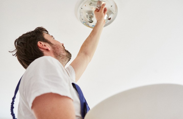 Mann montiert Deckenlampe.