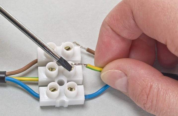 Mann verbindet Kabel in Lüsterklemme miteinander.