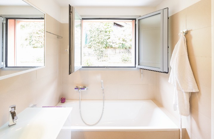 Ein Badezimmer mit geöffnetem Fenster über der Dusche.