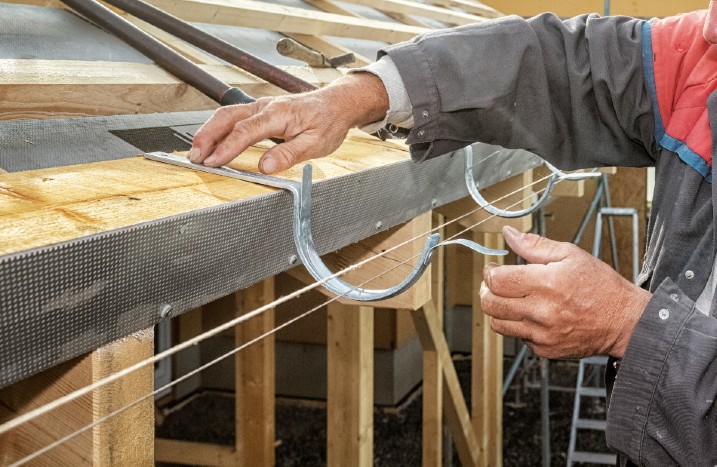 Handwerker hält Rinneneisen an Dach