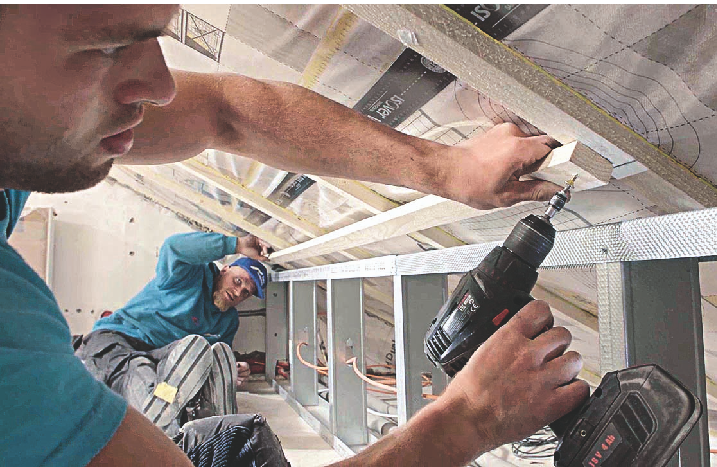 Gemeinsam schrauben zwei Handwerker Latten an die Dachschräge.