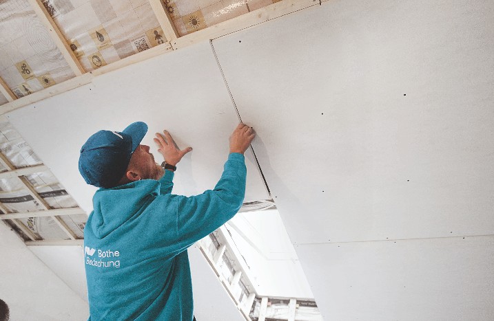 Handwerker verkleidet eine Dachschräge mit Gipskartonplatten.